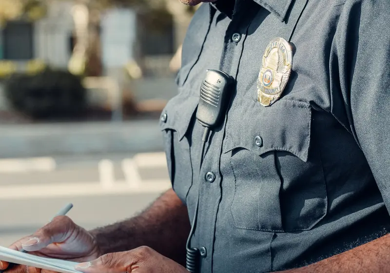 A police officer in uniform writes on a notepad.