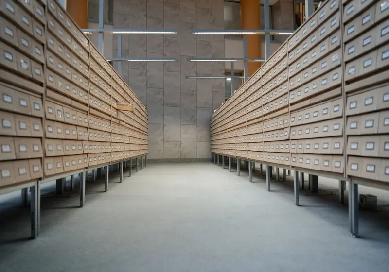 A long aisle of labelled wooden file drawers in a records room.