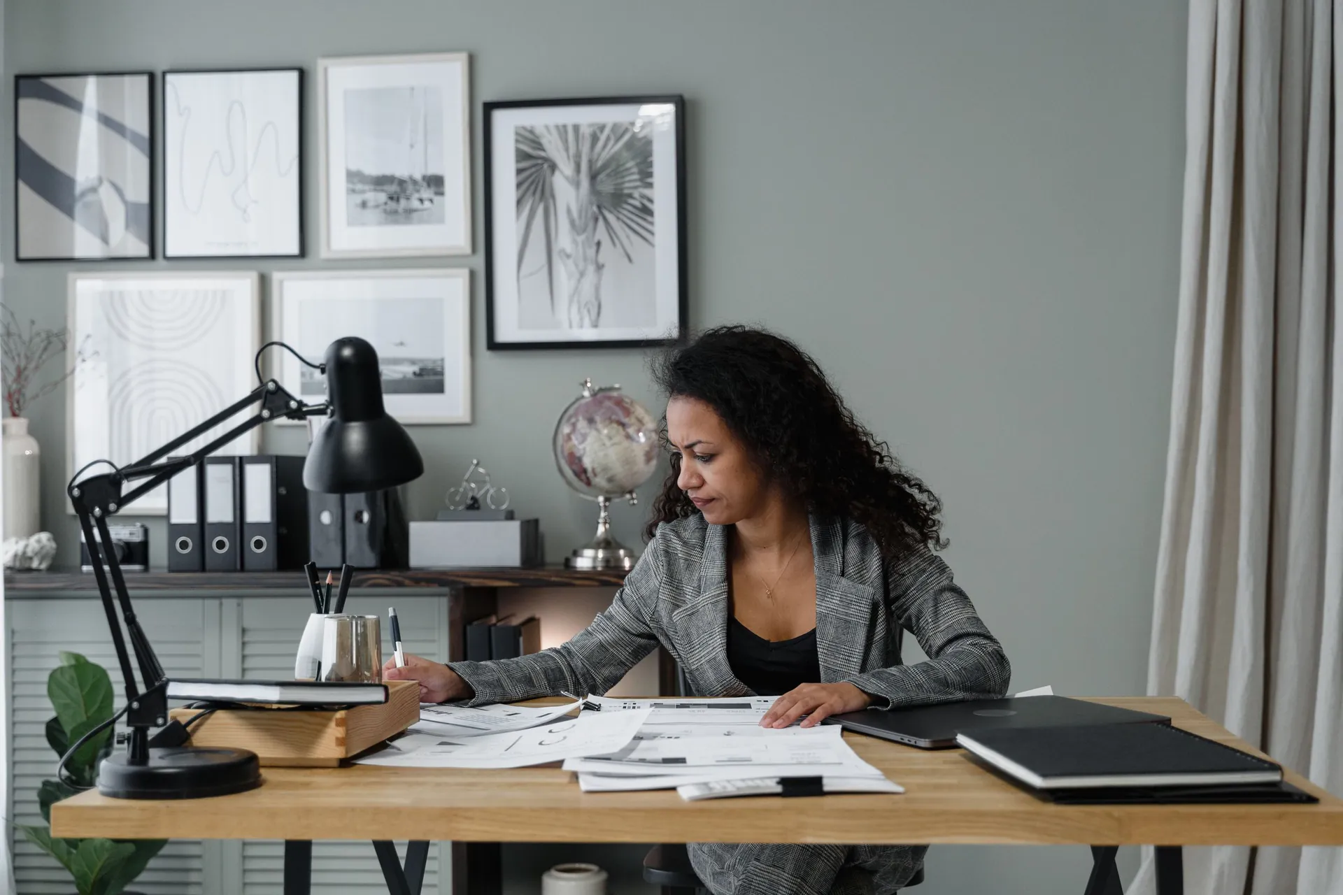 A clerk reviews papers at a desk beside a stack of files.
