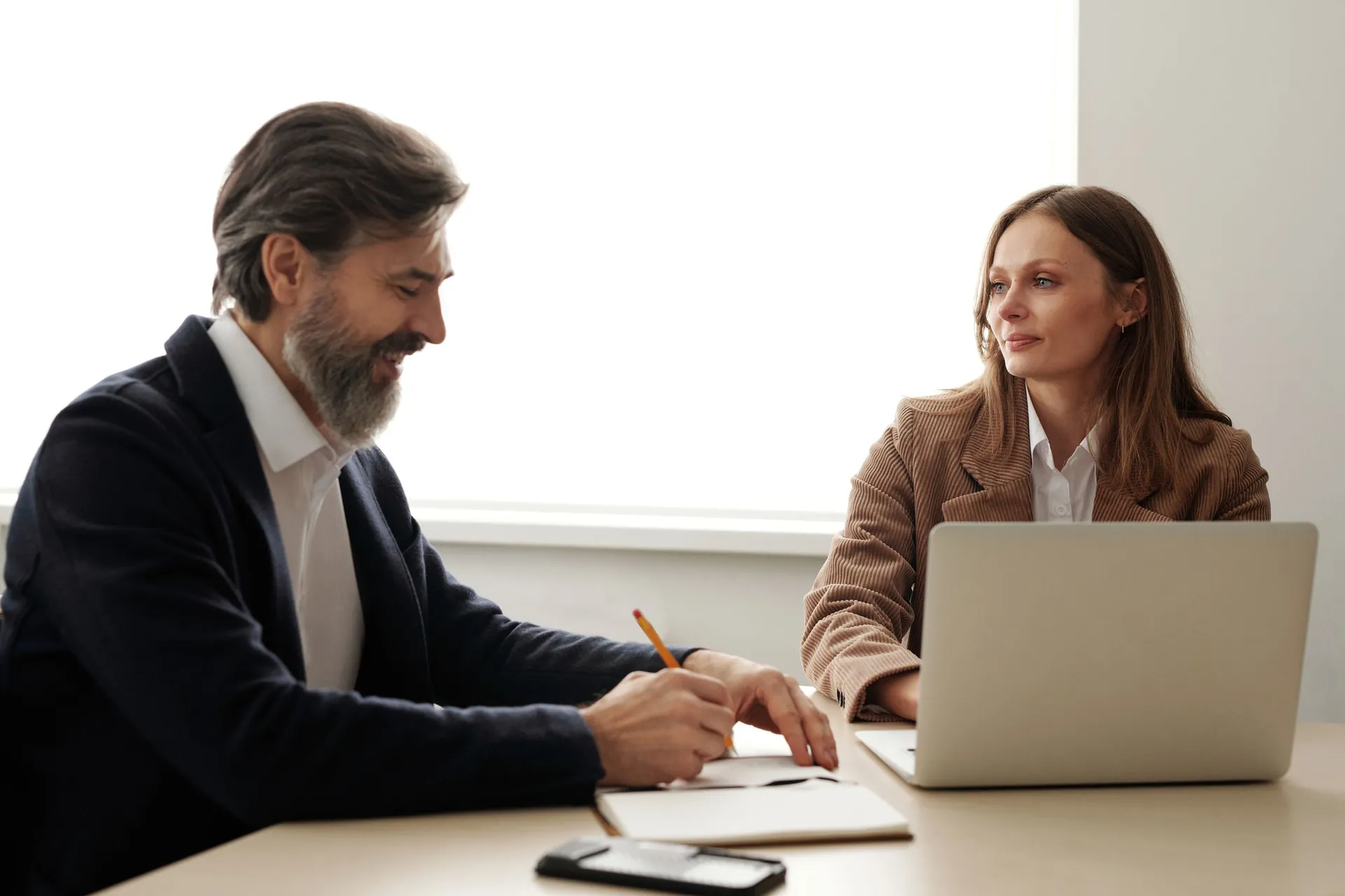 Two finance staff work together at a desk with a laptop.