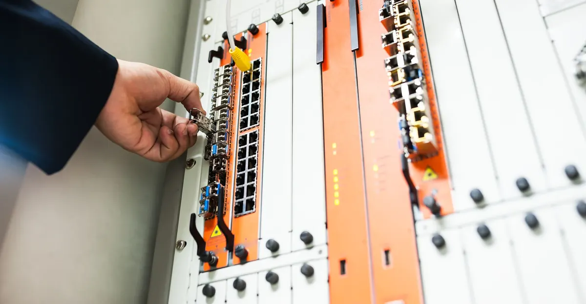 A hand fitting a module into network equipment in a rack.