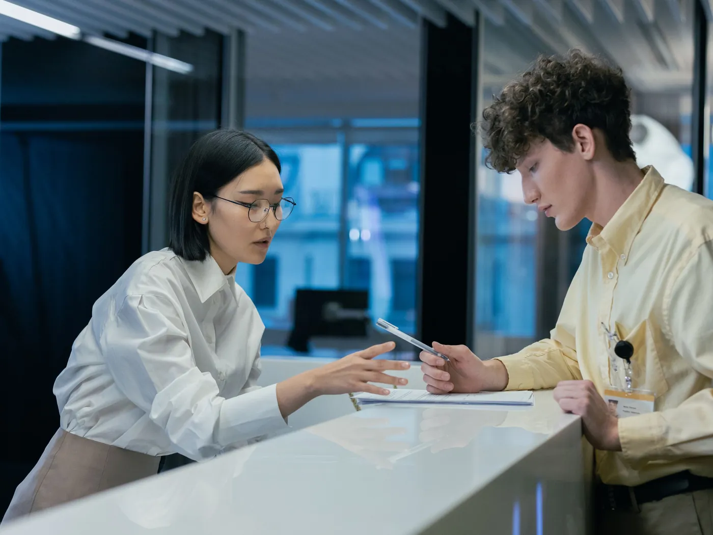 A city staff member helps a resident at a service counter.